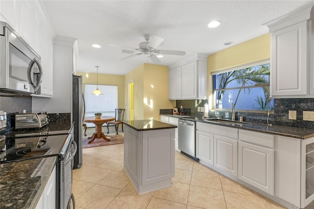 kitchen with a kitchen island, appliances with stainless steel finishes, tasteful backsplash, sink, and white cabinets