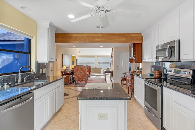 kitchen featuring a kitchen island, appliances with stainless steel finishes, sink, white cabinets, and dark stone counters