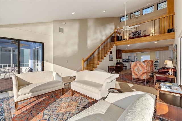 living room with a healthy amount of sunlight, ceiling fan, and a towering ceiling