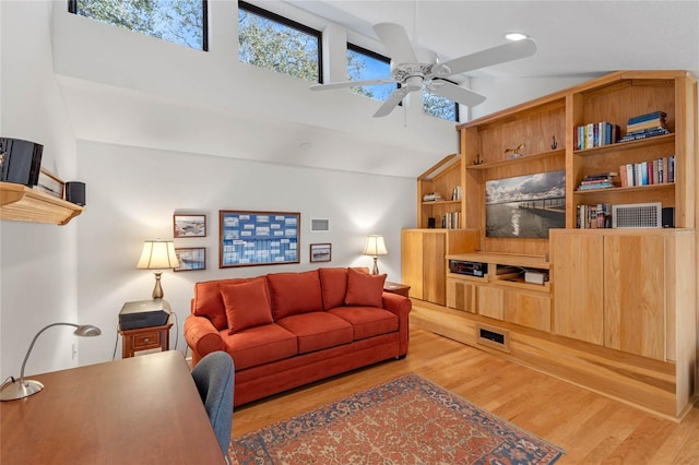 living room featuring built in shelves, ceiling fan, wood-type flooring, and vaulted ceiling