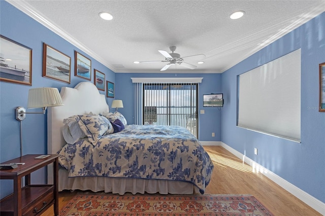 bedroom with ornamental molding, wood-type flooring, ceiling fan, and a textured ceiling