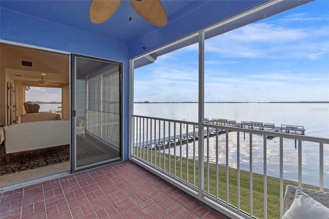 balcony featuring a wealth of natural light, ceiling fan, and a water view