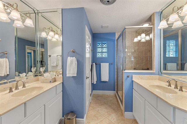 bathroom featuring tile patterned flooring, vanity, a shower with door, and a textured ceiling