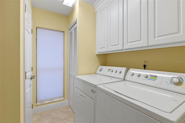 laundry area featuring cabinets, light tile patterned flooring, and washing machine and clothes dryer