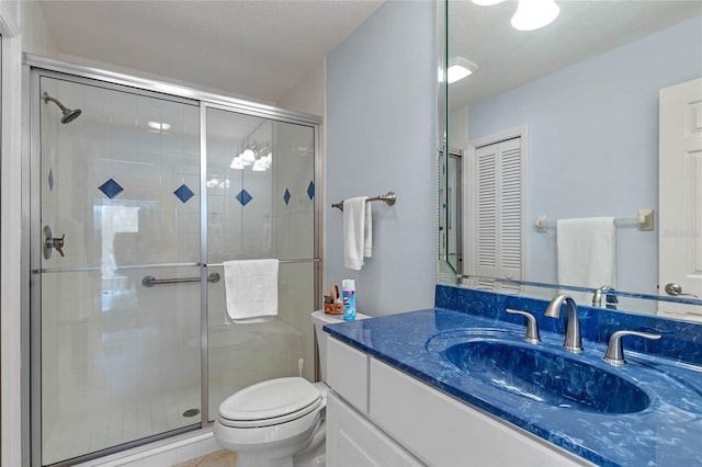 bathroom featuring vanity, toilet, a shower with door, and a textured ceiling