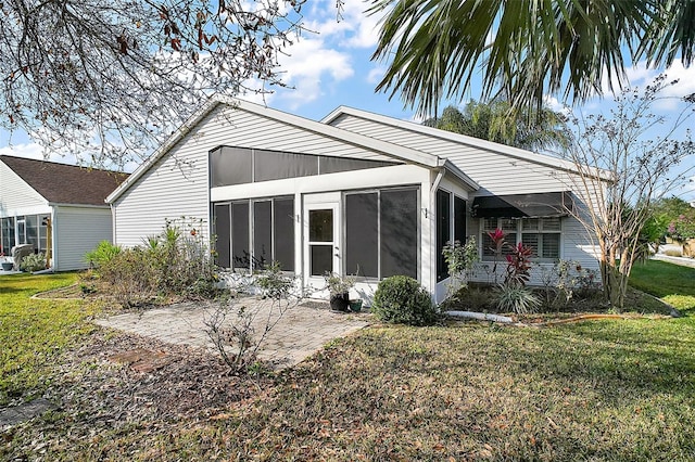 rear view of property featuring a lawn, a sunroom, and a patio area