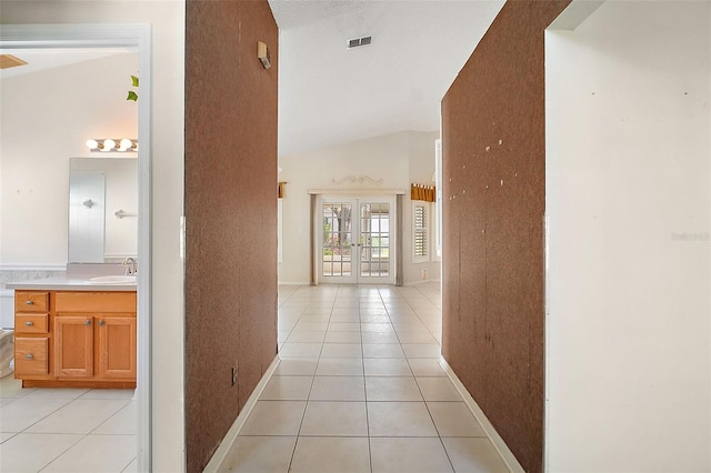 corridor with light tile patterned flooring, sink, high vaulted ceiling, and french doors