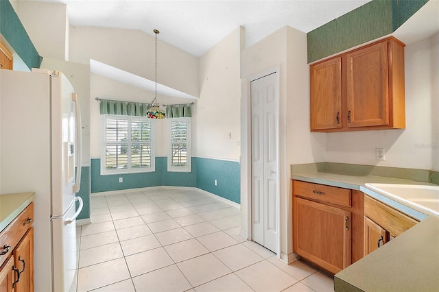 kitchen with vaulted ceiling, pendant lighting, sink, white refrigerator with ice dispenser, and light tile patterned floors