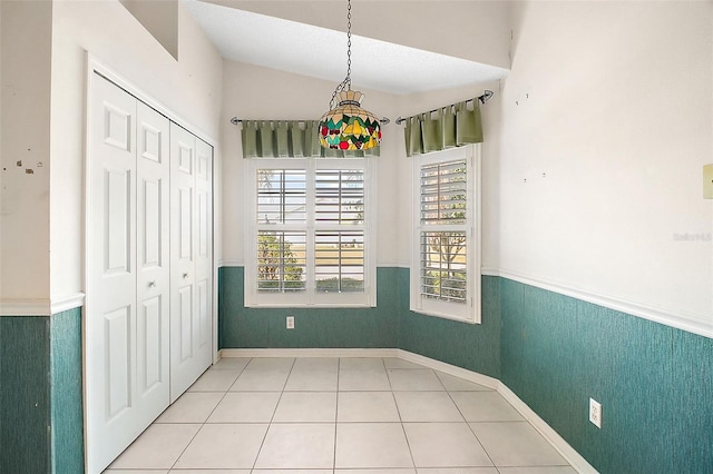 unfurnished dining area featuring lofted ceiling and tile patterned floors