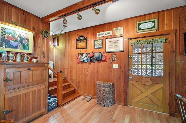 interior space with rail lighting, light hardwood / wood-style floors, and wood walls