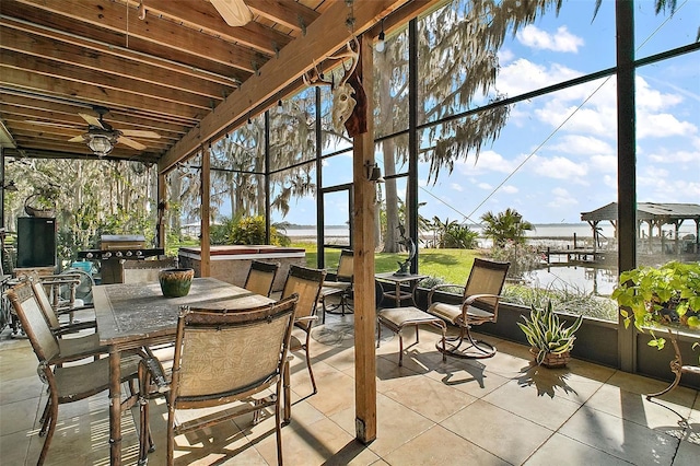 sunroom with ceiling fan and a water view