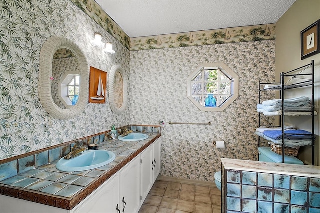 bathroom featuring vanity, toilet, tile patterned flooring, and a textured ceiling
