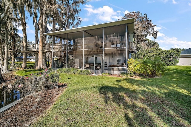 rear view of house with a lawn and a sunroom