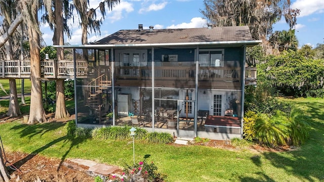 back of property with a yard and a sunroom