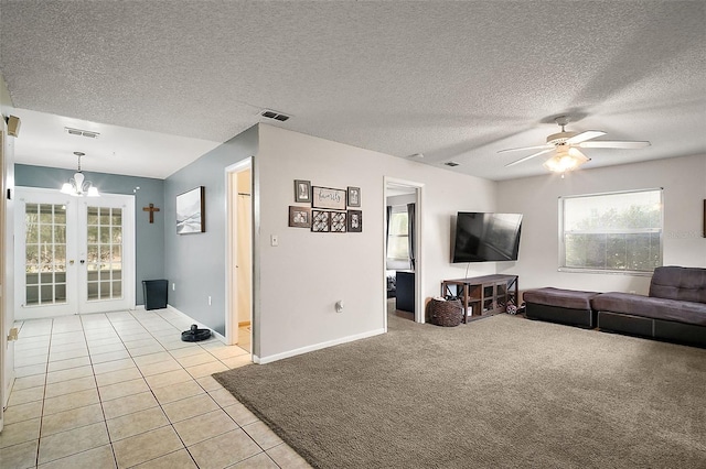 tiled living room with french doors, ceiling fan with notable chandelier, and a textured ceiling