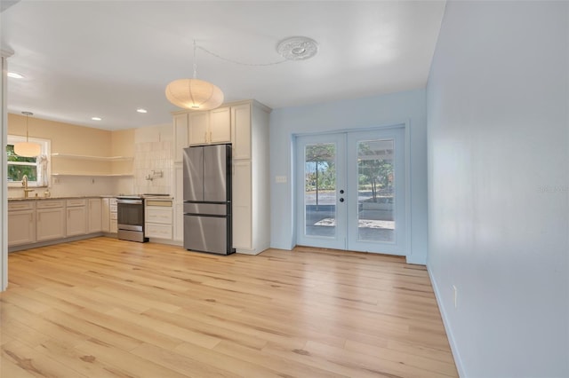 kitchen with decorative light fixtures, stainless steel appliances, white cabinets, and light wood-type flooring