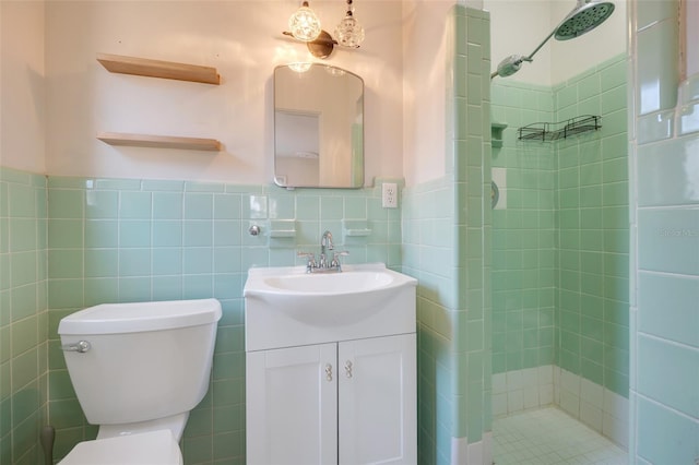 bathroom with tiled shower, vanity, toilet, and tile walls