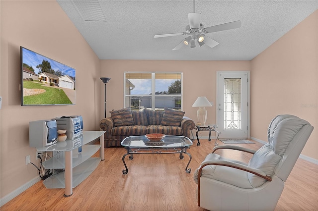 living room featuring ceiling fan, a textured ceiling, and light hardwood / wood-style flooring