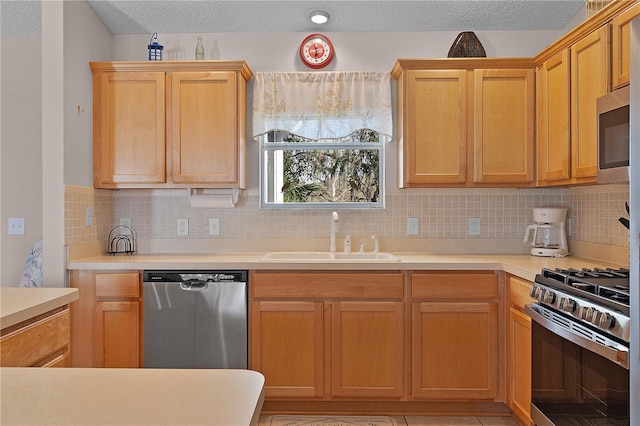 kitchen with sink, backsplash, a textured ceiling, and appliances with stainless steel finishes