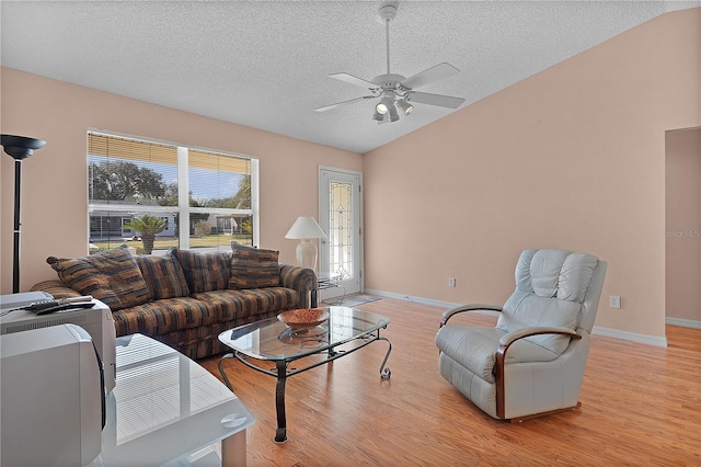 living room featuring ceiling fan, vaulted ceiling, a textured ceiling, and light wood-type flooring