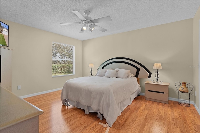 bedroom featuring ceiling fan, light hardwood / wood-style floors, and a textured ceiling