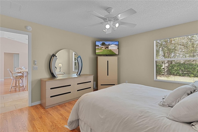 bedroom with ceiling fan, a textured ceiling, and light wood-type flooring