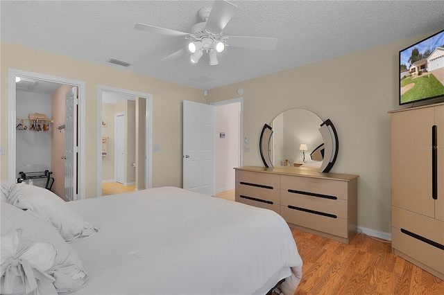 bedroom featuring ceiling fan, light hardwood / wood-style floors, and a textured ceiling