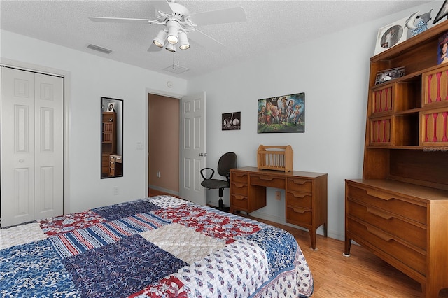 bedroom with ceiling fan, a closet, a textured ceiling, and light wood-type flooring