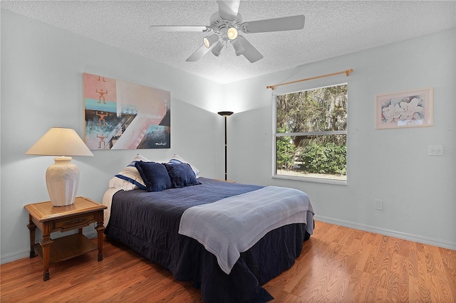 bedroom featuring ceiling fan, hardwood / wood-style flooring, and a textured ceiling