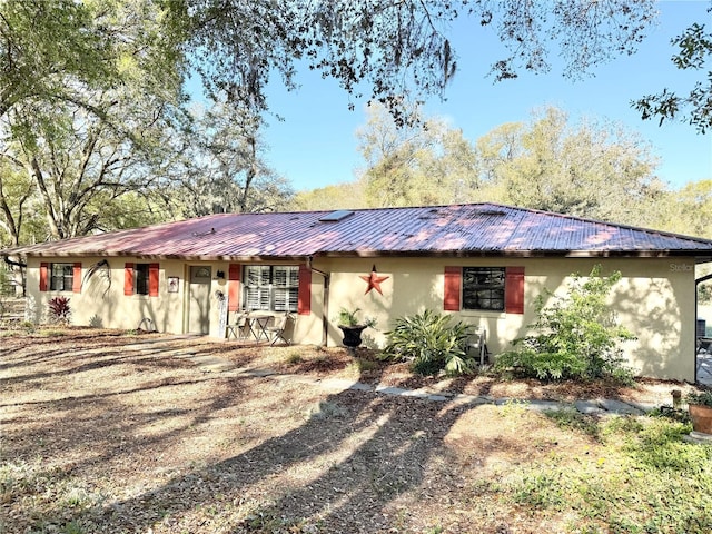 single story home featuring stucco siding and metal roof