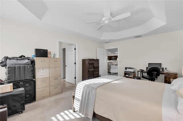 carpeted bedroom with ceiling fan and a tray ceiling