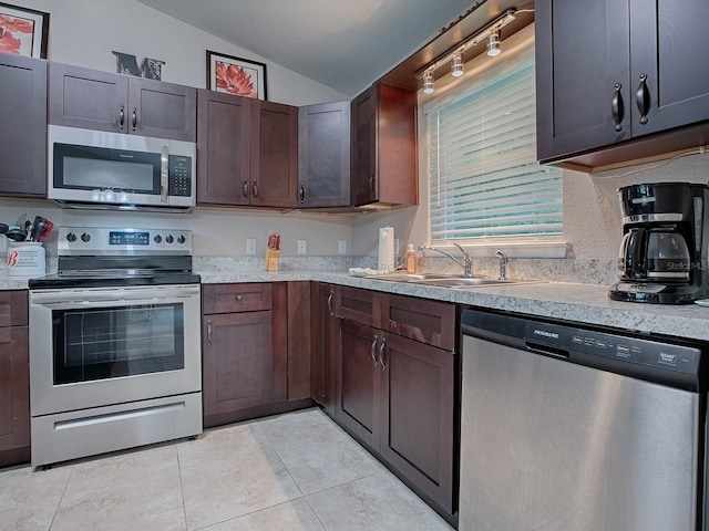 kitchen with light tile patterned floors, sink, appliances with stainless steel finishes, dark brown cabinets, and vaulted ceiling