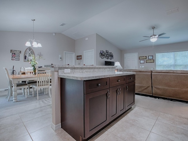 kitchen featuring lofted ceiling, a center island, dark brown cabinets, light tile patterned floors, and pendant lighting