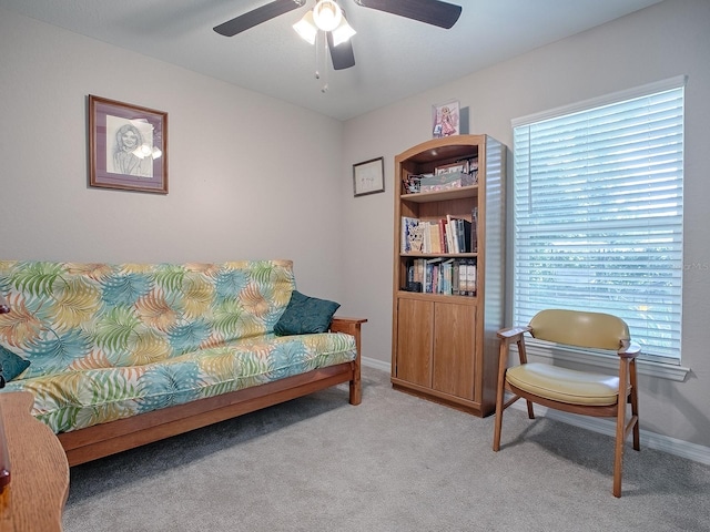 living area featuring light colored carpet and ceiling fan