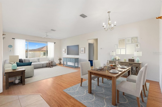 dining room featuring ceiling fan with notable chandelier and light hardwood / wood-style floors
