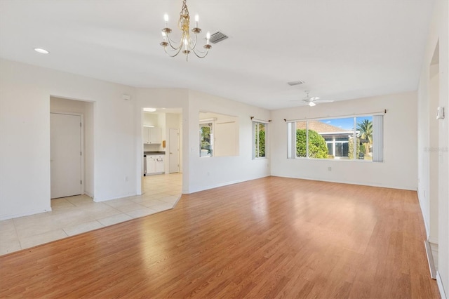 unfurnished living room featuring ceiling fan with notable chandelier and light wood-type flooring