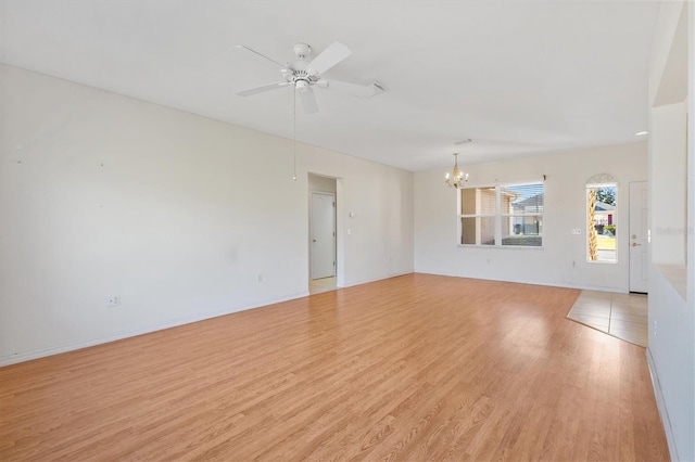 empty room with ceiling fan with notable chandelier and light wood-type flooring