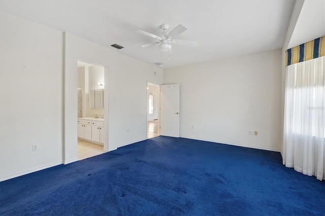 unfurnished bedroom with ceiling fan, ensuite bathroom, and light carpet
