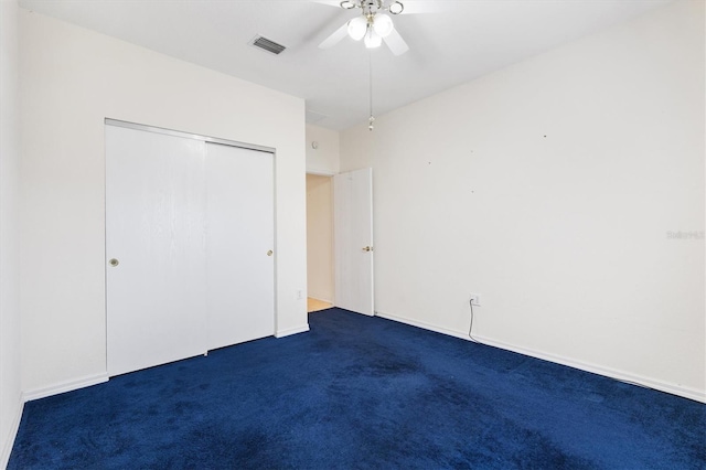unfurnished bedroom with ceiling fan, a closet, and dark colored carpet