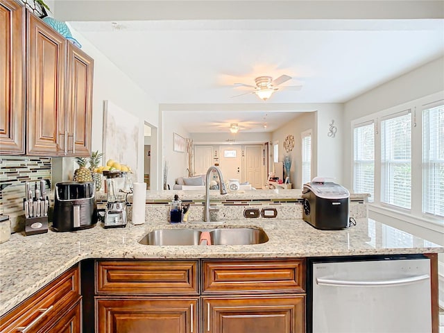 kitchen with sink, dishwasher, ceiling fan, light stone countertops, and decorative backsplash