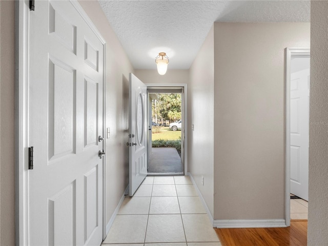 doorway to outside with light tile patterned floors and a textured ceiling