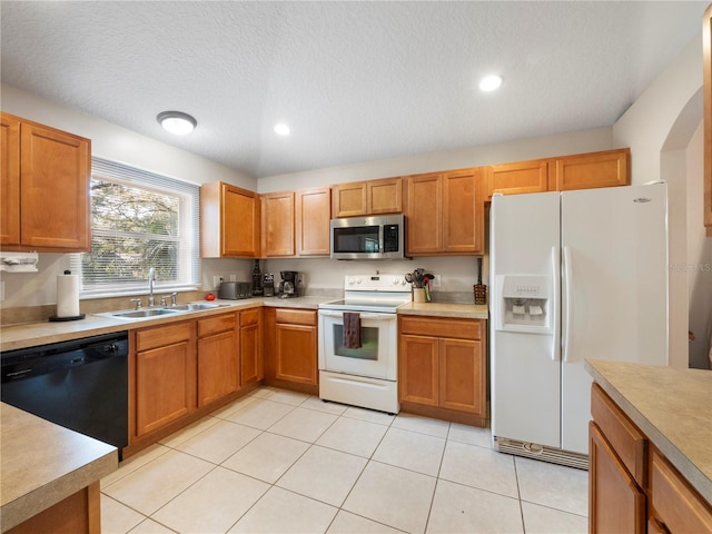 kitchen with white appliances, sink, a textured ceiling, and light tile patterned floors