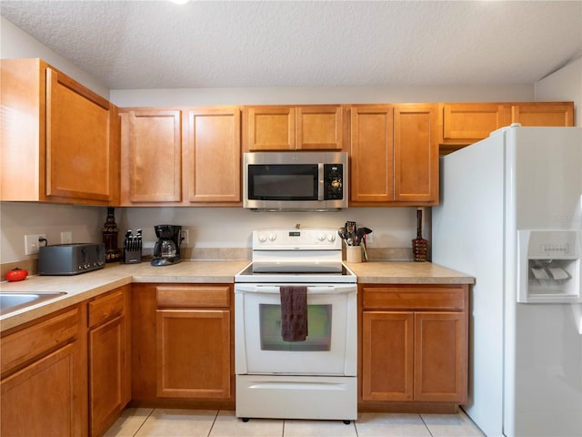 kitchen featuring white appliances, a textured ceiling, and light tile patterned floors