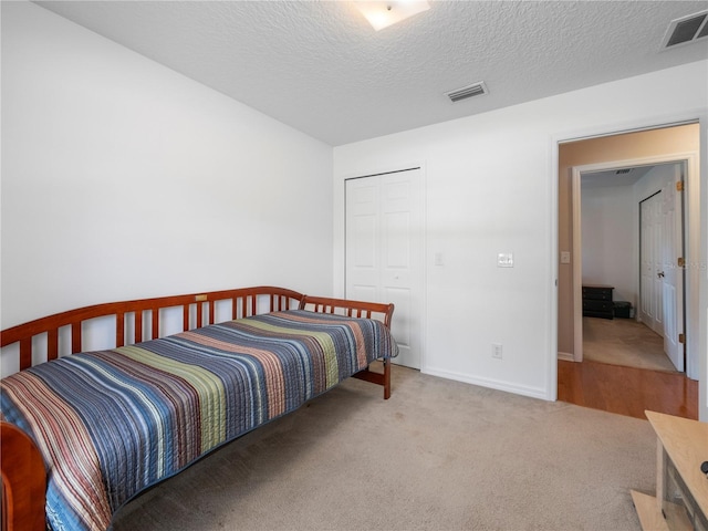 bedroom with light carpet, a textured ceiling, and a closet