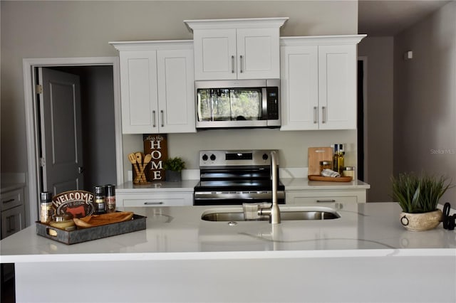 kitchen with white cabinetry, appliances with stainless steel finishes, and light stone counters