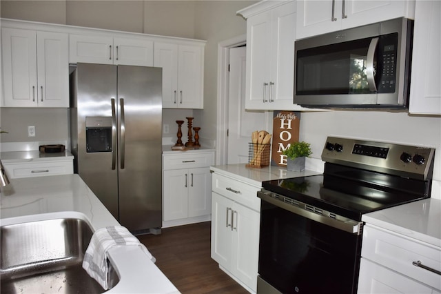 kitchen with light stone countertops, appliances with stainless steel finishes, dark wood-type flooring, and white cabinets