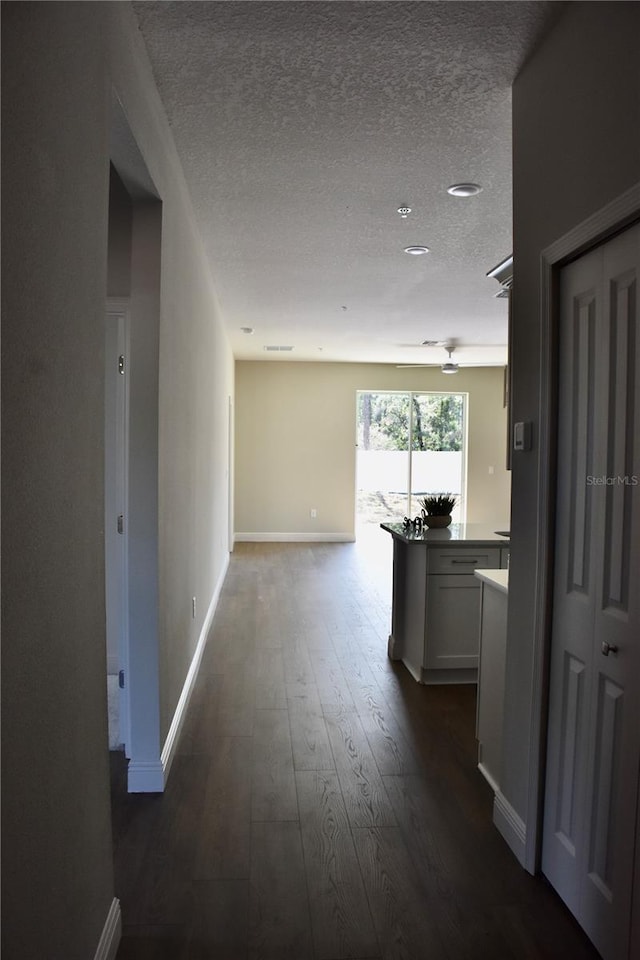 corridor with dark hardwood / wood-style floors and a textured ceiling