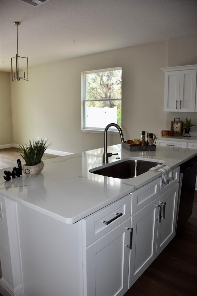 kitchen featuring sink, dark hardwood / wood-style floors, white cabinets, and a center island with sink