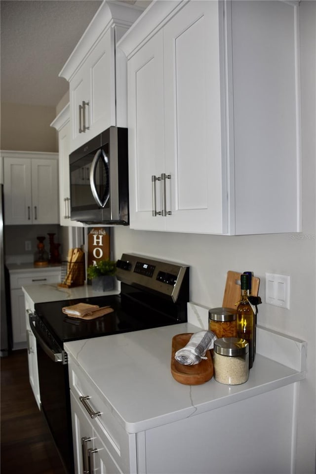 kitchen featuring stainless steel appliances, light stone countertops, and white cabinets