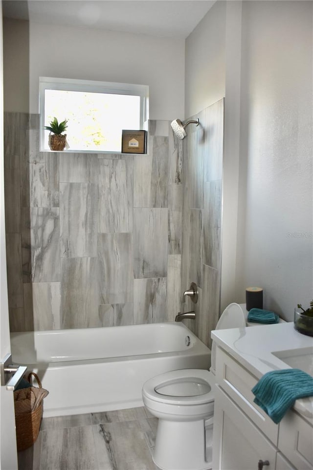 full bathroom featuring tiled shower / bath combo, vanity, wood-type flooring, and toilet